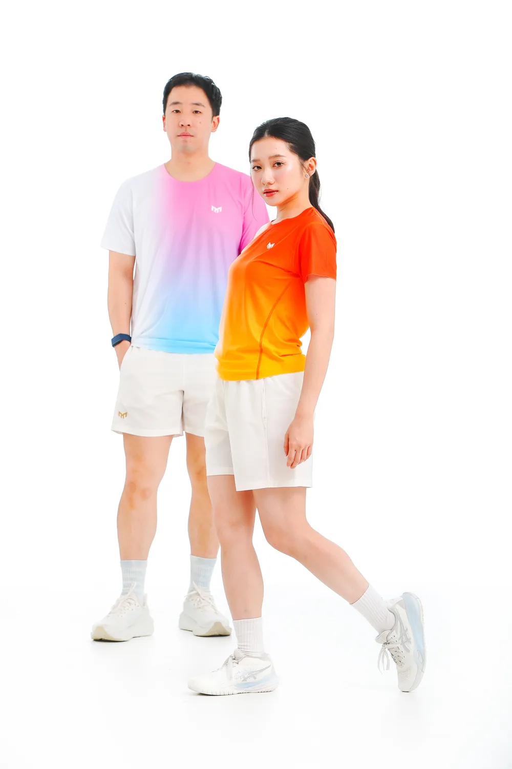 A man in a Cotton Candy T-shirt stands beside a woman striding in an Ember Fade T-shirt